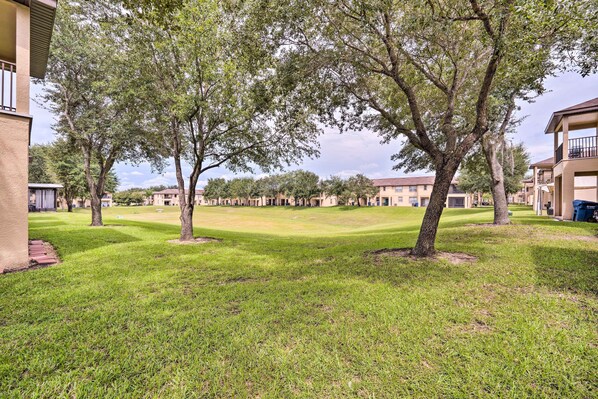 A courtyard with a lawn, trees, and multiple buildings with balconies. - 9 Mi to Disney: Davenport Resort Townhome (Davenport)