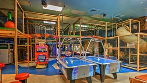 Ein Indoor-Erholungsbereich mit zwei Kicker-Tischen, Spielautomaten und einer großen Stofftier-Kuschelecke.