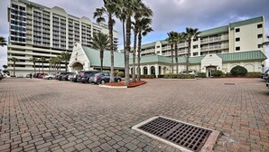 A hotel with a paved courtyard, palm trees, and a parking area. - Sunny Daytona Beach Gem w/ Ocean Views! (Daytona Beach)