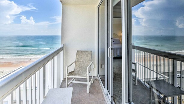 A balcony with a view of the ocean, a chair, and a small table. - Sunny Daytona Beach Gem w/ Ocean Views! (Daytona Beach)