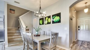 Un comedor con mesa y sillas de madera, una araña y decoración en las paredes.