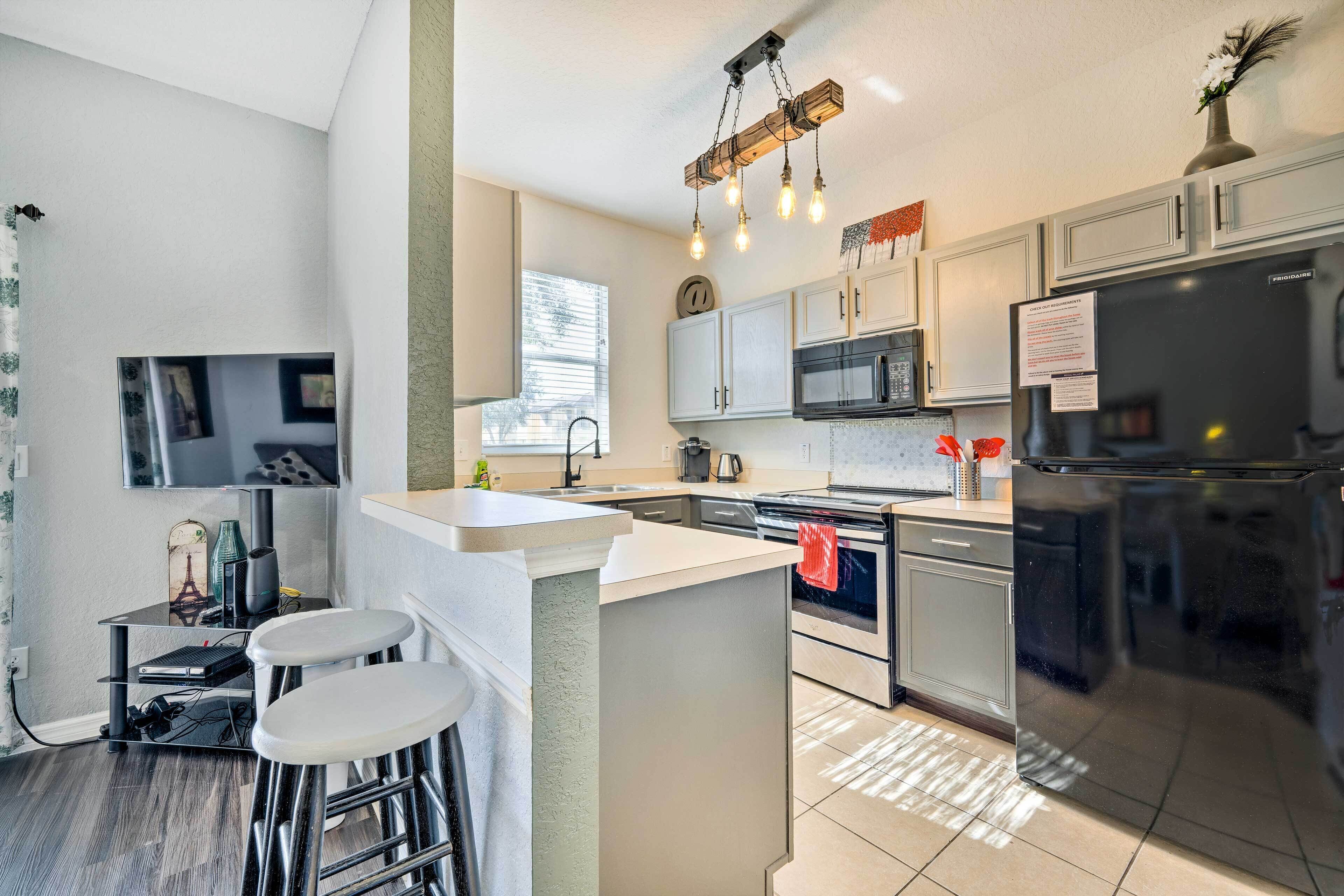 A modern kitchen with a central island, stainless steel appliances, and a bar stool area.