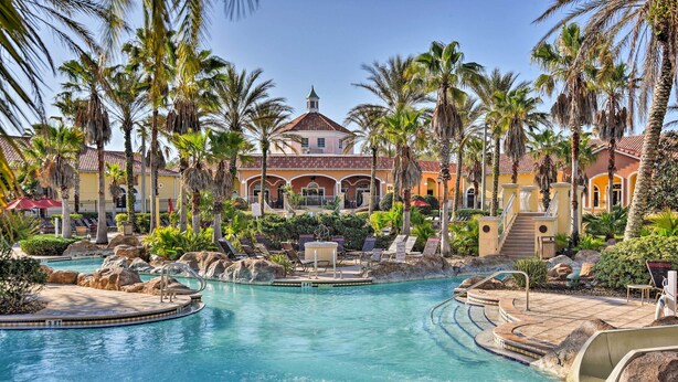 A resort with a large pool, palm trees, and a building with a red roof. - 9 Mi to Disney: Davenport Townhome w/ Resort Pool! (Davenport)
