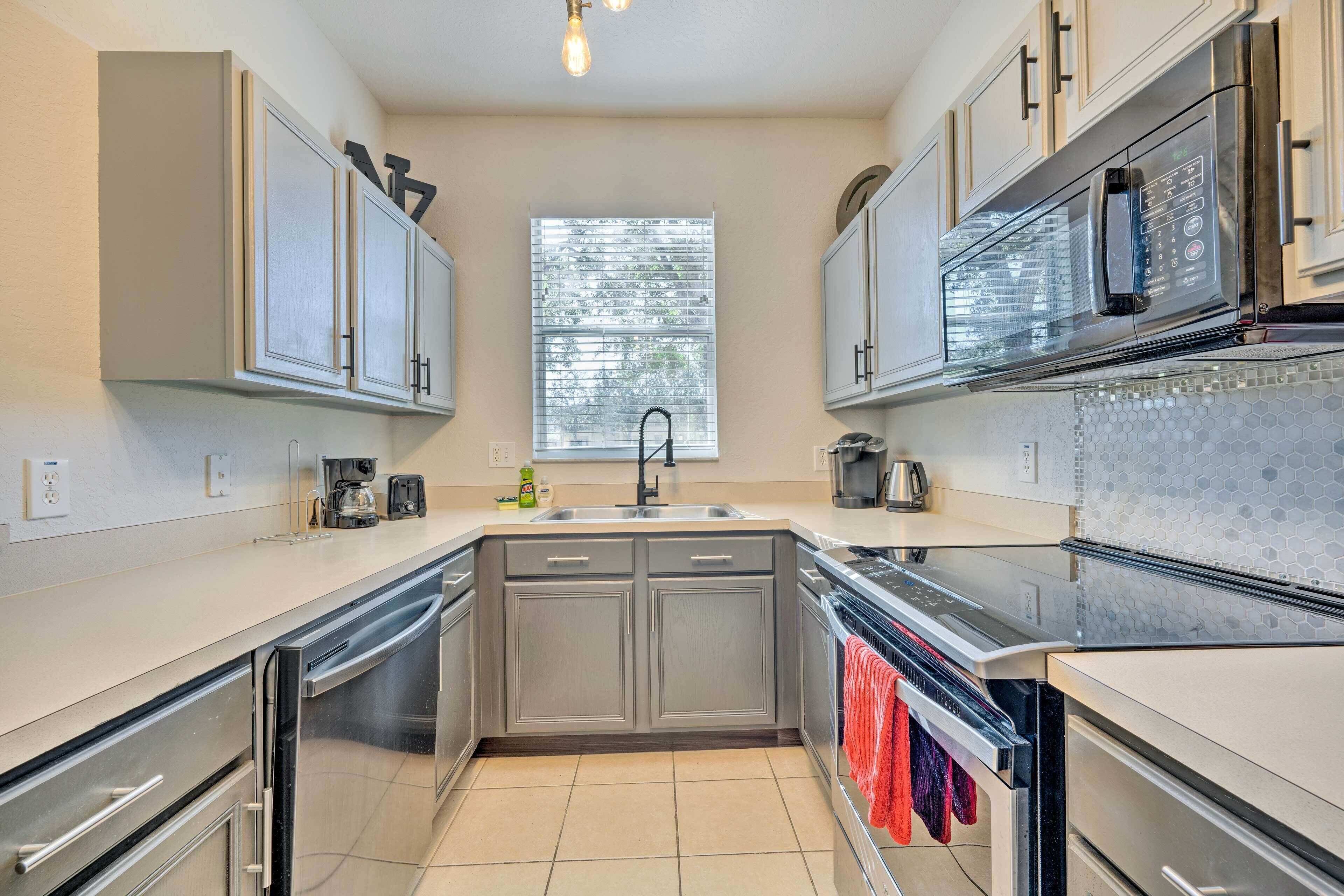 Una cocina moderna con electrodomésticos de acero inoxidable, un lavamanos doble y un ventanal que proporciona luz natural.