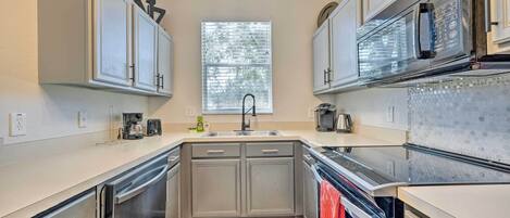 Una cocina moderna con electrodomésticos de acero inoxidable, un lavamanos doble y un ventanal que proporciona luz natural.