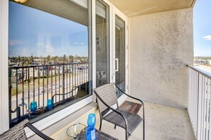 Un balcon donnant sur un parking et des immeubles, une chaise et deux vases bleus posés sur la table.