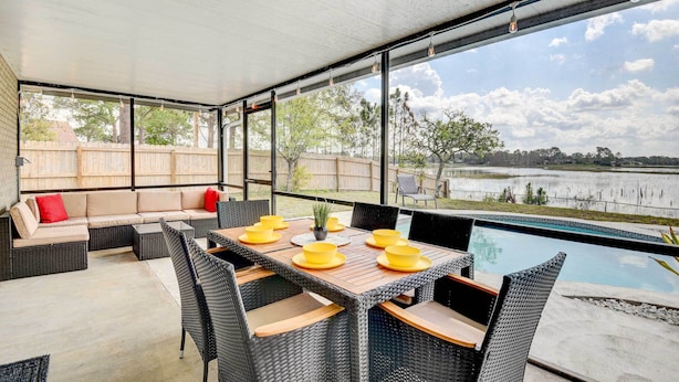 Ein überdachter Patio mit Pool, Sitzgelegenheiten im Freien und Blick auf einen See.