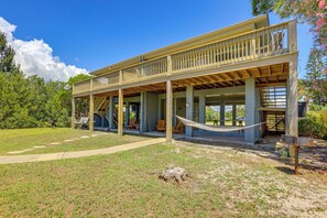 A two-story house with a covered porch and a hammock.