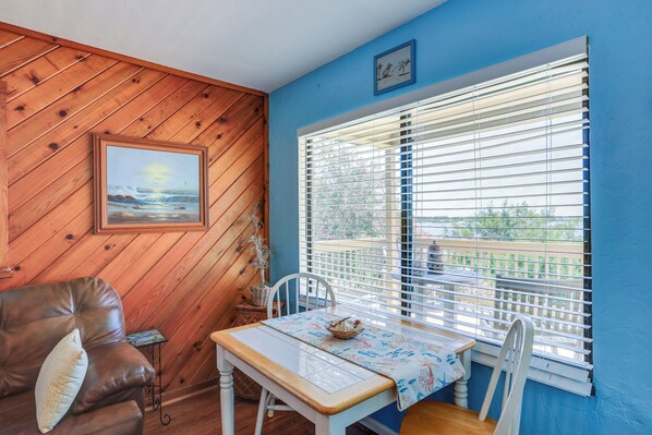 A room with a wooden ceiling, a dining table with a white tablecloth, a brown leather sofa, and a window with blinds. - Waterfront Duplex w/ Dock & Views: Near Town! (Cedar Key)