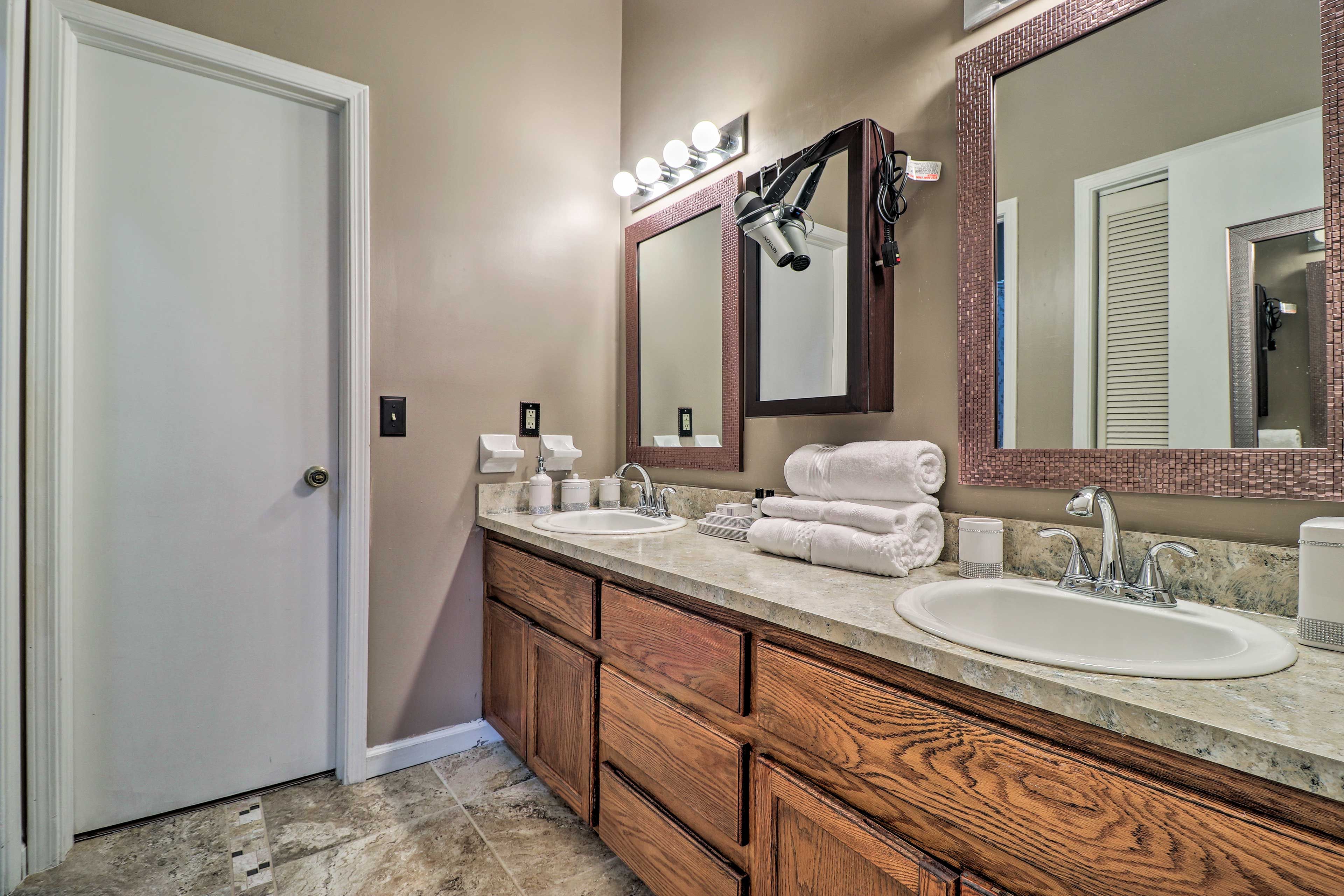 Une salle de bain avec deux lavabos, des meubles en bois, un grand miroir et une porte.
