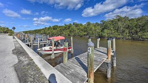 A dock with a boat, a sign, and a forested area. - Everglades City Cabin: Dock & Heated Pool! (Everglades City)