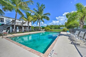 Una piscina con indicador de profundidad de 1 metro 18 centímetros, rodeada de palmeras y sillas de descanso.