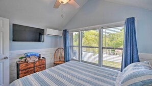 A bedroom with a bed, a chair, a dresser, a ceiling fan, and a window with curtains. - Everglades City Cabin: Dock & Heated Pool! (Everglades City)
