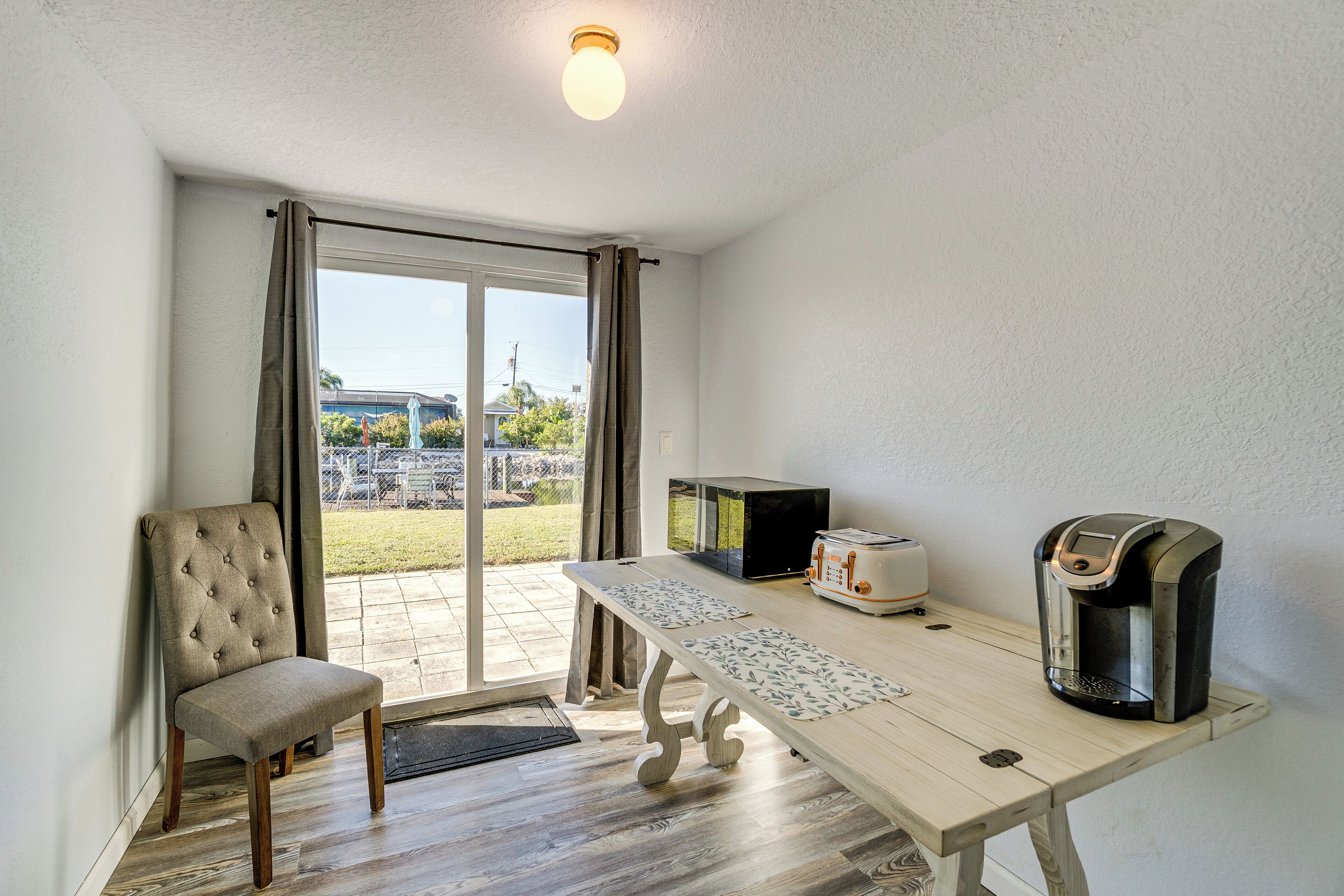 A room with a dining table, a microwave, a toaster, and a coffee maker.