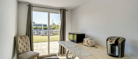 A room with a dining table, a microwave, a toaster, and a coffee maker.