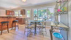 A kitchen with a wooden bar, a round table with four chairs, and a decorative metal rack with glassware. - Family Home w/ Private Pool & Fenced Yard! (Fort Walton Beach)