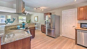 A modern kitchen with granite countertops, stainless steel appliances, wooden cabinets, and a white door. - Family Home w/ Private Pool & Fenced Yard! (Fort Walton Beach)