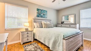 A bedroom with a bed, nightstands, a dresser, a ceiling fan, and a window with blinds.