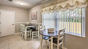 A dining area with a table and chairs, a window with blinds, and a door.