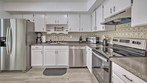 A modern kitchen with white cabinets, stainless steel appliances, and a patterned backsplash. - Family-friendly Ocala Retreat: 18 Mi to Dtwn! (Ocala)
