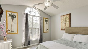 Ein Schlafzimmer mit einem großen Bett, einem Deckenventilator und einem Fenster mit Vorhängen.