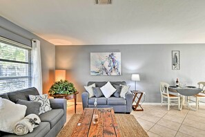 A modern living room with a grey sofa, a coffee table, and a dining area with a white table and chairs. - Florida Home 3 Mi to Siesta Key, Walk to Gulf Gate (Sarasota)
