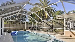 A covered swimming pool with a clear view of the surrounding area, including a wooden fence and palm trees. - Florida Home 3 Mi to Siesta Key, Walk to Gulf Gate (Sarasota)