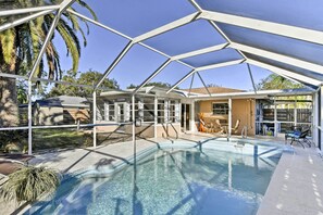 A covered outdoor swimming pool with a clear blue water feature, surrounded by a metal frame structure, and adjacent to a building with a tiled roof. - Florida Home 3 Mi to Siesta Key, Walk to Gulf Gate (Sarasota)