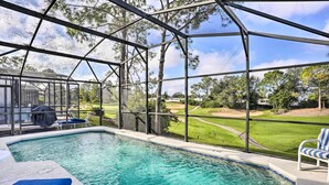 Piscina com vista para um campo de golfe, rodeada por uma estrutura de metal.