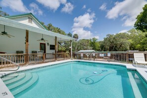 A clear blue swimming pool with steps leading into it, surrounded by a wooden deck and a covered area with chairs. - Pool Access: Homosassa Home Near Boat Launch! (Homosassa)