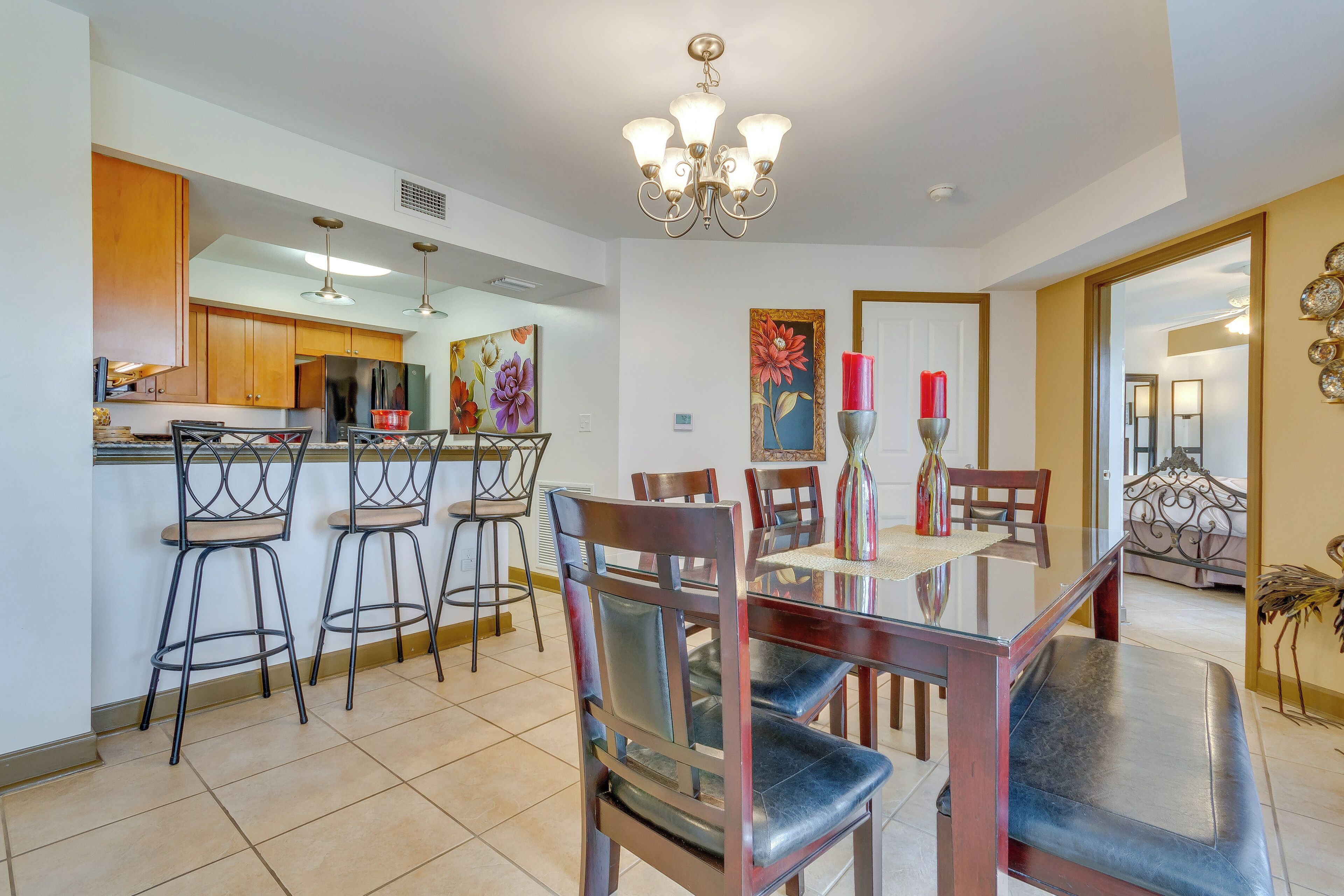 A dining area with a wooden table and chairs, a chandelier, and artwork on the walls.