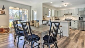 A modern kitchen with light green cabinets, a central island, and a dining area with four chairs. - 'green Acres' Home w/ Fire Pit + Fishing Pond (Molino)