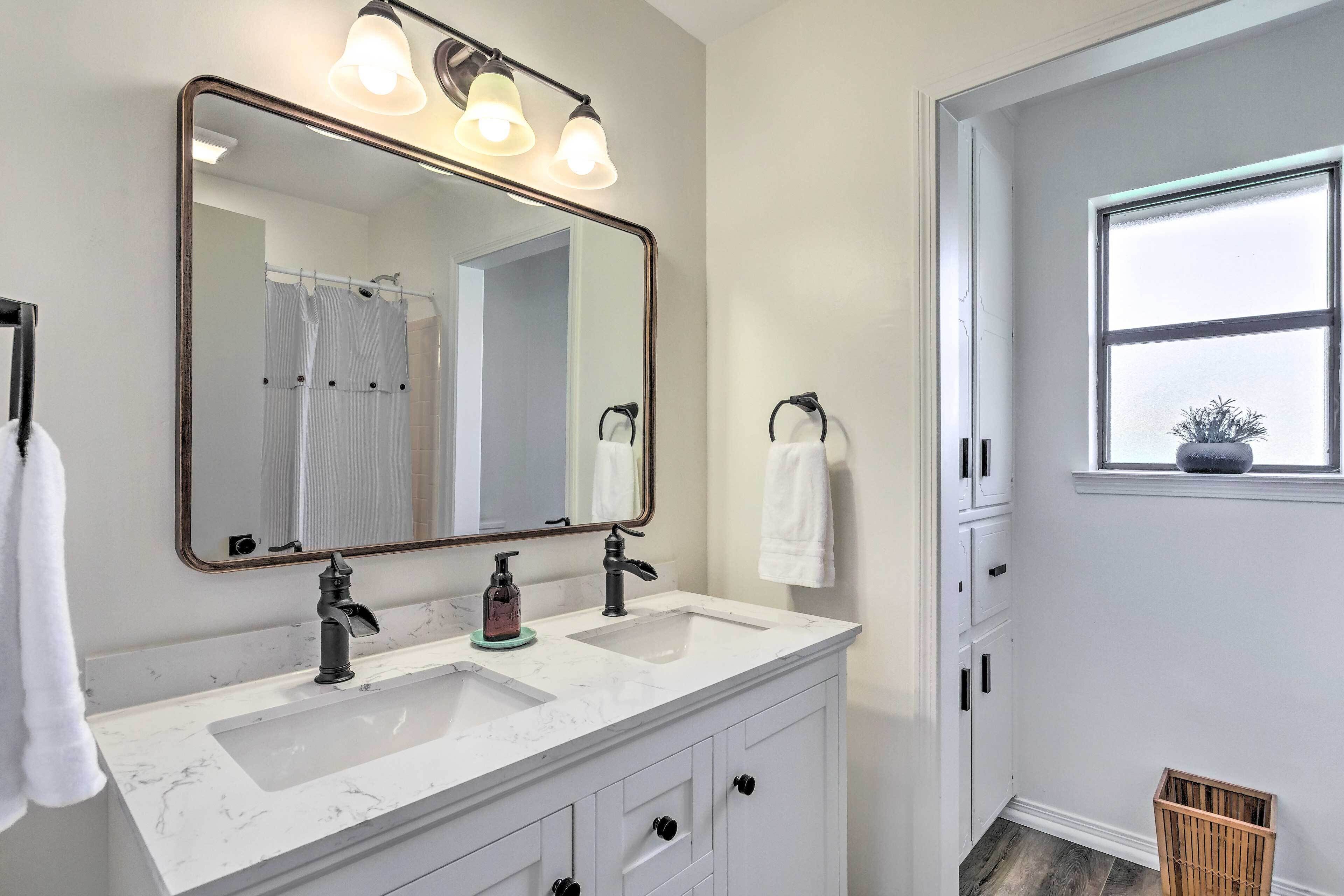 A bathroom with two sinks, a large mirror, and a window.
