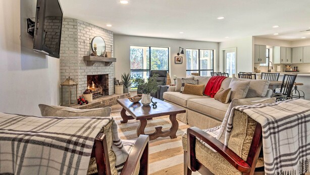 A living room with a fireplace, a sofa, a coffee table, and a television mounted on the wall. - 'green Acres' Home w/ Fire Pit + Fishing Pond (Molino)
