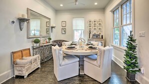 Un coin repas avec une table ronde, des chaises à revêtement blanc, un miroir décoratif et un sapin de Noël.