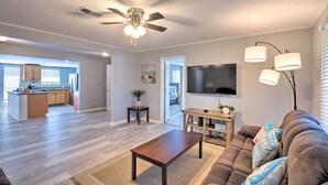 A spacious living room with a ceiling fan, a flat-screen TV, and a comfortable couch.
