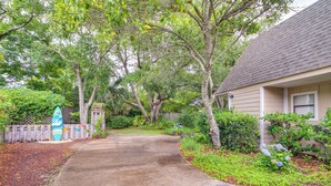 A residential driveway leading to a house with a covered porch, surrounded by lush greenery and a wooden fence. - 5 Mi to Pensacola Beach: Townhome w/ Yard! (Gulf Breeze)