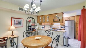 A kitchen with a round wooden table, chairs, a chandelier, and various appliances. - 5 Mi to Pensacola Beach: Townhome w/ Yard! (Gulf Breeze)