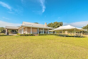 A two-story building with a covered porch and a large tent set up in the front lawn. - House w/ Wraparound Porch, 1/2 Mi to Lake! (Lady Lake)