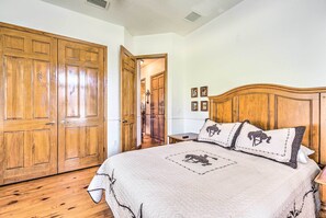 A bedroom with a large wooden wardrobe, a bed with a quilted cover, and two nightstands. - House w/ Wraparound Porch, 1/2 Mi to Lake! (Lady Lake)