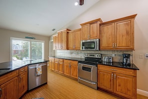 A kitchen with wooden cabinets, stainless steel appliances, and a window with blinds. - Walk to Beach & JW Marriott Heated Pool (Marco Island)