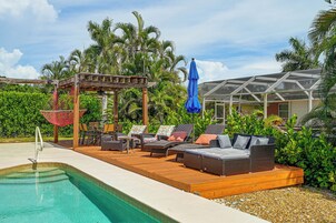 A poolside area with lounge chairs, a hammock, and a covered seating area.