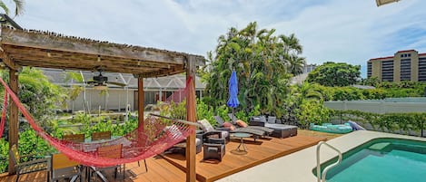 Ein Poolbereich mit Holzterrasse, einer Hängematte, Gartenmöbeln und einem Pool.