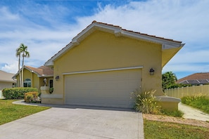 A residential house with a garage, a driveway, and a well-maintained lawn. - Walk to Beach & JW Marriott Heated Pool (Marco Island)