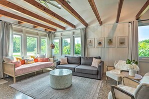 A cozy living room with a wooden ceiling, a grey sofa, a pink sofa, and a round coffee table. - Hutchinson Island Cottage: Steps to the Beach (Fort Pierce)