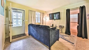 A room with a dark blue sofa, a television, a door with a glass panel, and a window with curtains. - Jacksonville Getaway w/ Yard ~ 2 Mi to Beach! (Atlantic Beach)
