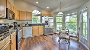 A spacious kitchen with wooden cabinets, stainless steel appliances, and a dining area with a table and chairs. - Kissimmee Escape w/ Lanai & Private Pool! (Kissimmee)