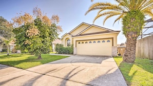 A residential house with a garage, a lawn, and a palm tree. - Kissimmee Escape w/ Lanai & Private Pool! (Kissimmee)