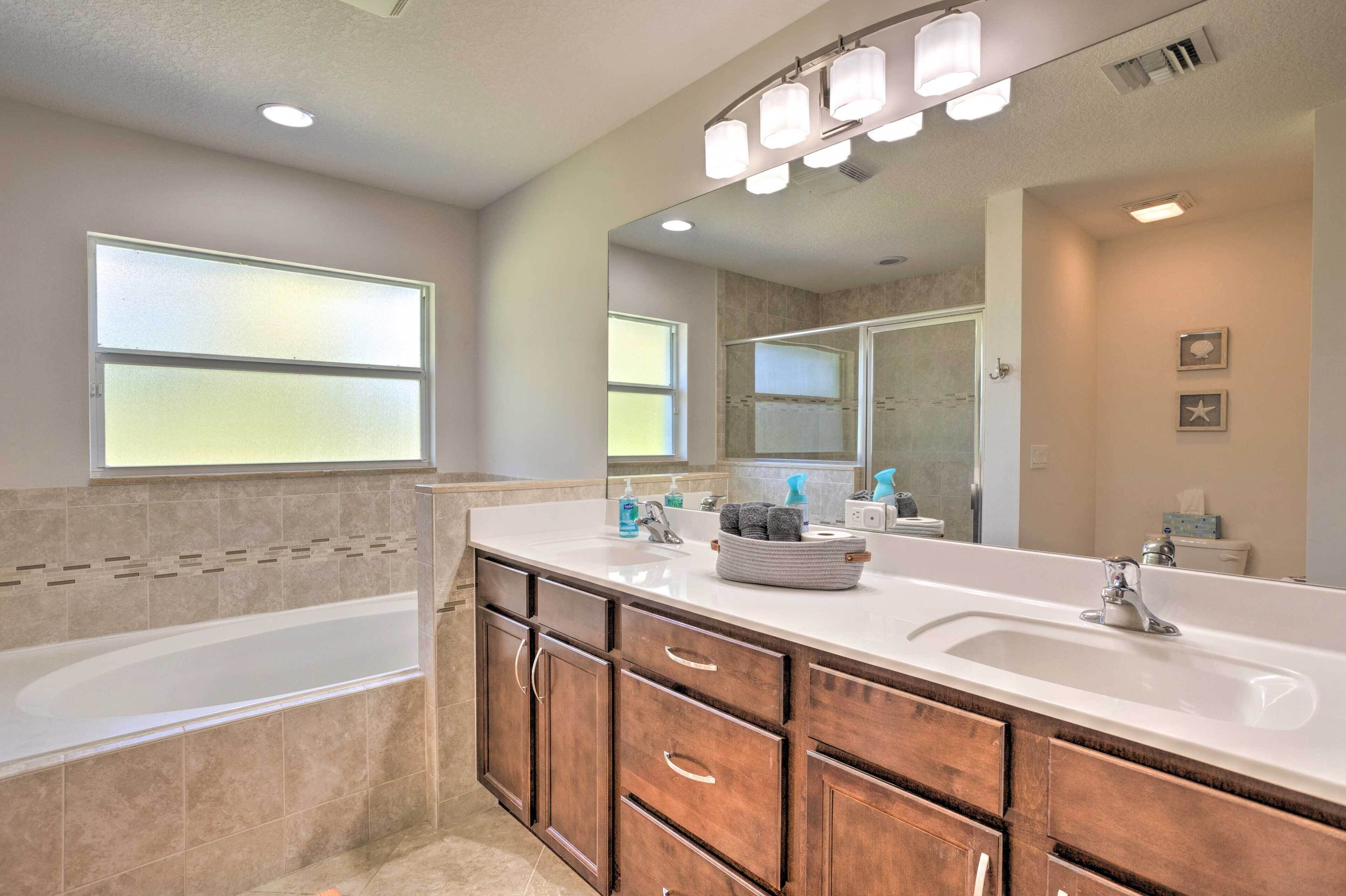 A modern bathroom with a large bathtub, a double sink vanity, and a large mirror.