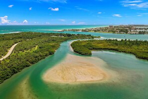 An aerial view of a coastal area with a curving waterway, dense greenery, and a distant urban settlement. - Private Pool & Steps to Ocean: Island Beach House! (Fort Pierce)